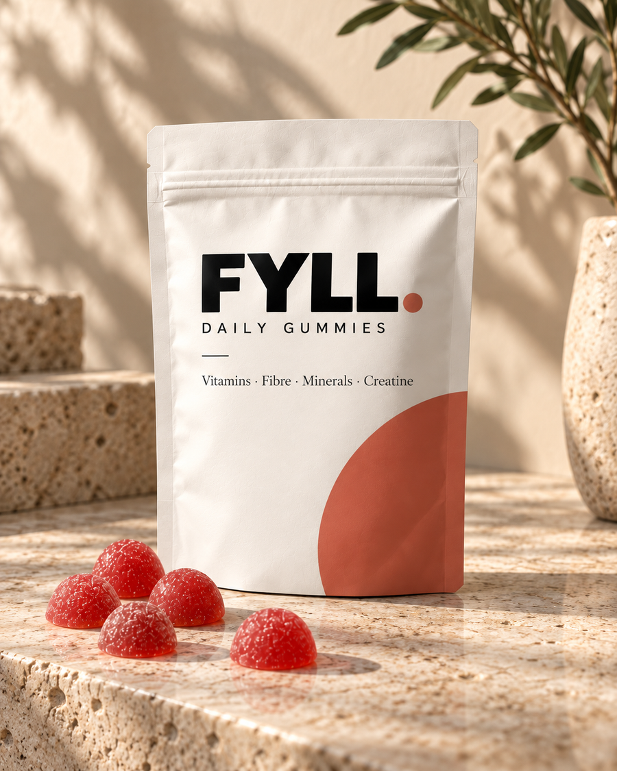 FYLL Daily Gummies packaging concept: an ivory pouch with a terracotta accent and red gummies on warm stone.